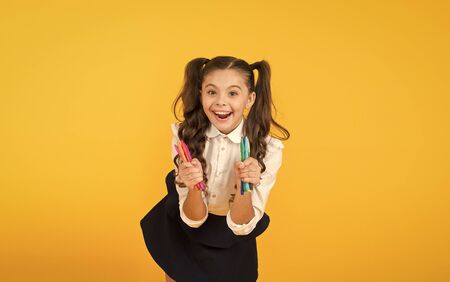 Happy arts. Happy little artist. Happy girl holding colorful markers on yellow background. Cheerful small child with happy smile and drawing pens. Enjoying arts and craftsの写真素材