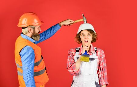 Intelligibly concept. Couple renovating apartment together. Man and woman wear safety helmet. Couple making repair at home. Home Renovation. Rub in. Couple knocking head with hammer. Clearly explainの写真素材