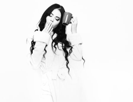 yawning girl in beige velour bathrobe holding cupの写真素材