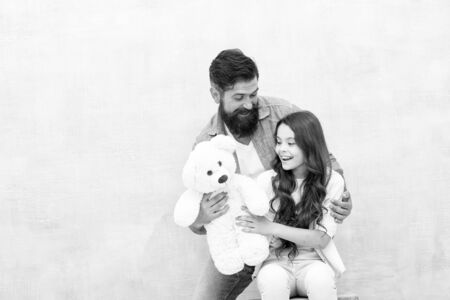 Giving soft toy teddy bear. Lovely father and kid. Father and daughter light background. Strengthening father daughter relationships. Child and dad best friends. Family relations. Fathers day conceptの写真素材