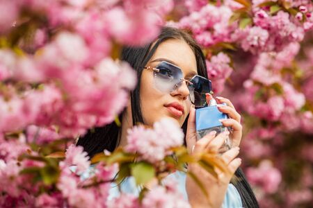 Luxury fragrance. Fashionable woman hold perfume bottle. Cherry blossom aroma. Female perfume. Spring perfume. Fancy style. Aromatic compounds. Tenderness. Give pleasant scent. Eau de Toiletteの写真素材