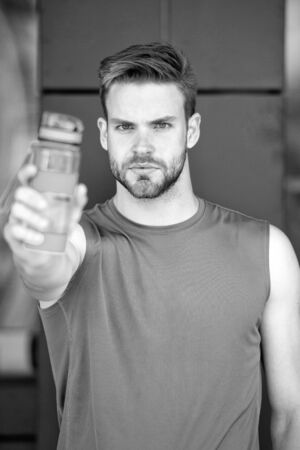 Bearded man share water with you. Presenting product. Thirst and health. Athlete hold plastic bottle. Drink some water. Stay hydrated and healthy after training. Sport and fitnessの写真素材