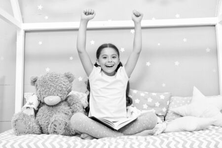 Finished reading book. Girl child sit bed with teddy bear finished reading book. Kid ready to go to bed. Finally finished that book. Girl kid long hair cute pajamas relax and read book to bear toyの写真素材