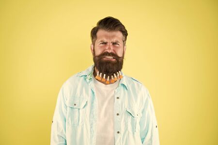 it hurts so much. individual hairstyle for male. man clothespin on beard. brutal hipster with clothespin hearts. bearded man casual style yellow background. valentines day. hair drying in hairdresserの写真素材
