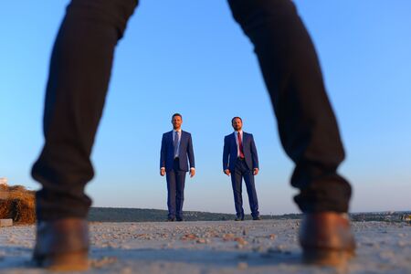 Business meeting and new partnership concept. Male legs wearing classic trousers make defocused frame, close up. Businessmen in formal suits on blue background. Pair of leaders stand in distanceの写真素材