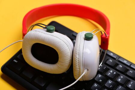 Earphones in red and white colors with computer keyboard. Sound recording and technology. Headphones...