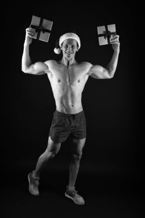 Santa claus for adult girls. Sexy athletic macho muscular chest in santa claus hat. Athlete man wear santa hat. I have gift for you. Handsome santa concept. Macho muscular torso posing with gift boxの写真素材