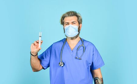 health worker dials vaccine in syringe. Physician or nurse giving vaccine against virus. coronavirus epidemic from china. mature doctor use syringe in respirator mask. skilled nurse make injectionの写真素材