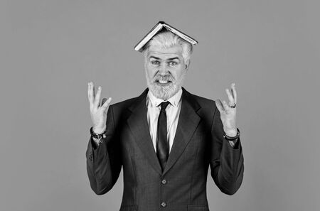 angry businessman notebook on head. mature man dyed beard and hair. tired reading book. too much work. daily schedule. male professional teacher. after barbershop. business school educationの写真素材