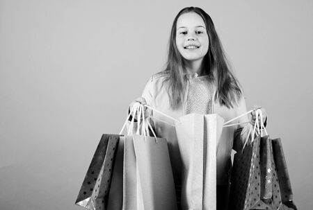 Kid fashion. shop assistant with package. Holiday purchase saving. Small girl with shopping bags. Sales and discounts. Happy child. Little girl with gifts. Taking all. copy space on blue backgroundの写真素材