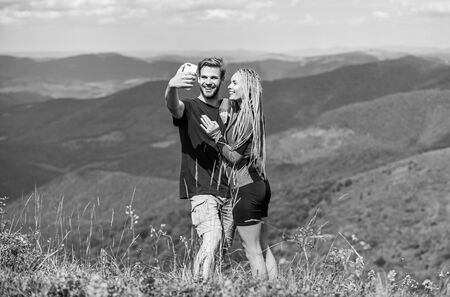 Couple taking photo. Summer vacation concept. Young adventurers. Travel together with darling. Couple in love hiking mountains. Lets take photo. Capturing beauty. Man and woman posing mobile photoの写真素材