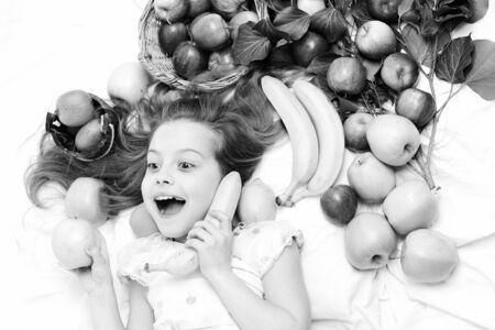 child, cute baby girl laying with colorful fruitsの写真素材