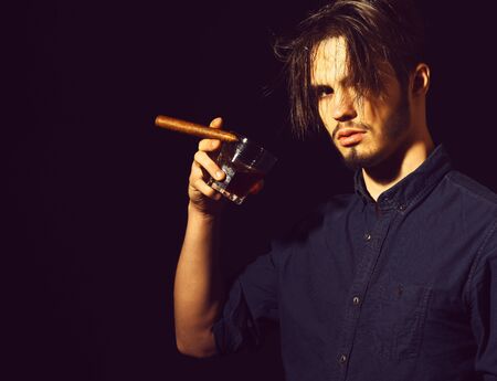 serious bearded man with whisky in black studio backgroundの写真素材