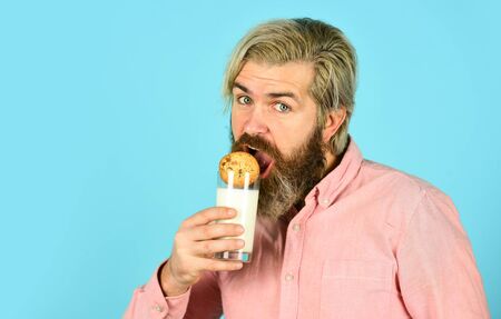bearded man drink useful milk with pastry. The concept of healthy eating. Organic farm products for Breakfast or lunch. milk and cookies. happy farmer eat cookie dessertの写真素材