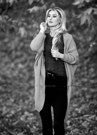 Girl adorable blonde posing in warm and cozy outfit autumn nature background defocused. Cozy outfit ideas for weekend. Woman walk sunset light. Clothing for every day. Cozy casual outfits for fallの写真素材