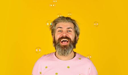 Summer vacation. Infantility concept. Happy playful bearded hipster and soap bubbles. Happiness and joy. Good mood. Play with bubbles. Forever young guy. Positive. Carefree man soap bubblesの写真素材