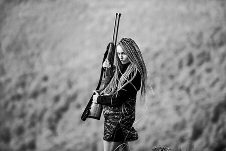 She is warrior. Woman attractive long hair pretty face hold rifle for hunting. Dangerous girl. Defending concept. Warrior mountains landscape background. Feminist girl. Hunting season. Sexy warriorの写真素材