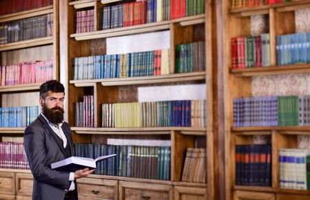 Bookstore and literature concept. Brutal man holds book in bookstore.の写真素材