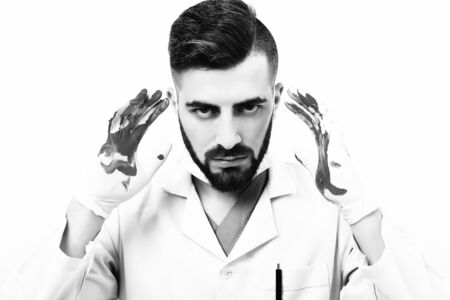 Man with beard in medical uniform with hands in bloodの写真素材