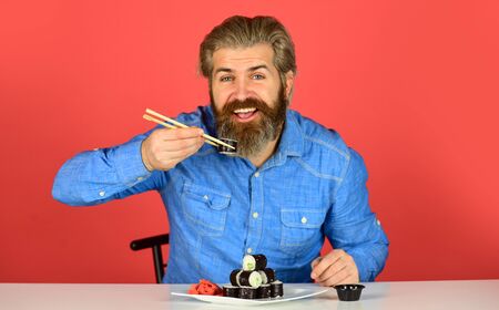 dinner at home. hipster eat sushi with chopsticks. tasty sushi roll. traditional and healthy food in japan. japanese sushi dish. man eating traditional Japanese food with chopsticksの写真素材