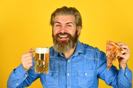 Beer and food. Dinner at pub. Hungry man going to eat pizza and drink beer. Finally pizza time. Pizzeria restaurant. Cheerful man bearded hipster eat pizza. Could not be better. Pizza party conceptの写真素材