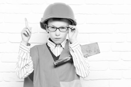 young cute builder boy on white brick wall backgroundの写真素材