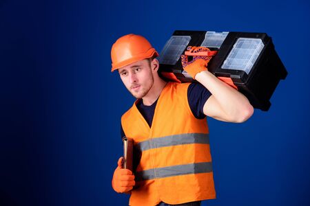 Man in helmet, hard hat holds toolbox and folder with documents, blue background. Repair service...
