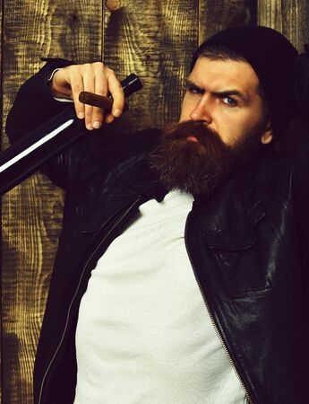 Bearded brutal caucasian hipster holding bottle and smoking cigar