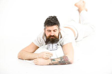 Guy with sleepy face lies on alarm clock.の写真素材
