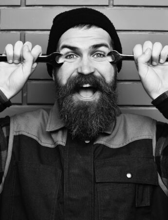 Bearded brutal caucasian mechanic holding metallic wrenches