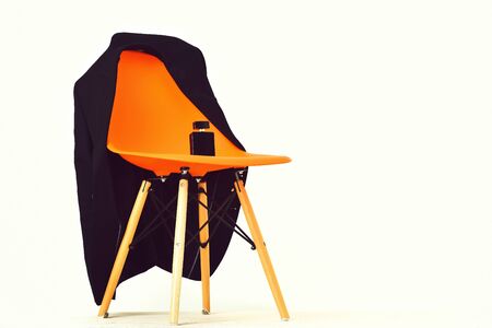 Orange plastic office chair with black jacket and bottle of perfume isolated on white backgroundの写真素材
