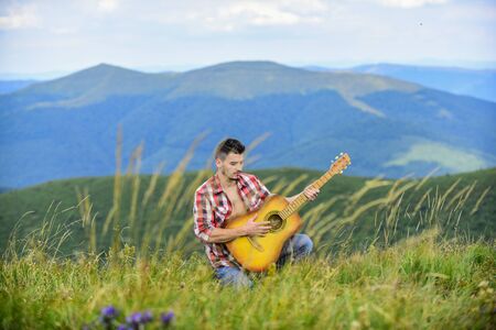 Inspired musician play rock ballad. Compose melody. Inspiring environment. Acoustic music. Summer music festival outdoors. Playing music. Sound of freedom. Man with guitar on top of mountainの写真素材