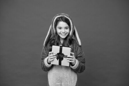 Gift perfect for holidays. Happy child hold gift box. Little girl in pyjamas with gift. Gift for Christmas or New year. Boxing day. Birthday anniversary. Special occasion present or purchaseの写真素材