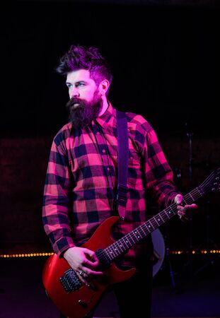 Man with calm face holds guitar, singing song, play musicの写真素材