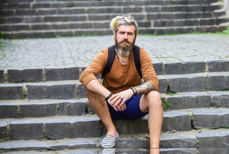 bearded man hipster relax outdoor. brutal male sit on stairs. fashion model wear casual clothes. mature man with beard and moustache. male barbershop style. dyed and healthy hairの写真素材