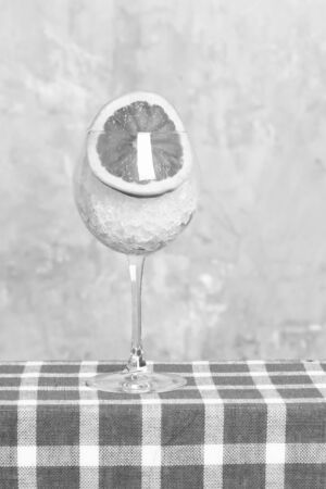 Glass for cocktail with ice and piece of orange in selective focus on blue checkered plaid on beige blurred background. Bar conceptの写真素材