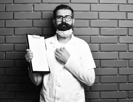 Bearded brutal caucasian doctor or postgraduate student with clipboardの写真素材