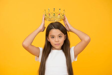 Lady little princess. Compelling baby. Kid wear golden crown symbol of princess. Girl cute baby wear crown while stand yellow background. Become princess concept. Every girl dreaming to be princessの写真素材