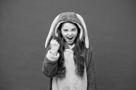 Yes I can. Lifestyle concept. Rest and relax. Cute bunny kid on red background. Baby animal character role. Gorgeous girl in bunny costume. Child in rabbit kigurumi. Happy girl in bunny pajamasの写真素材