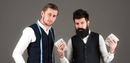 Tailors, clothes designers counting money, grey background.