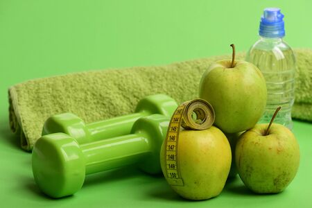 Dumbbells in green color, bottle, measure tape, towel and fruitの写真素材