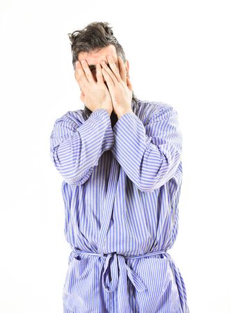 man in blue robe yawns, covering face with hands,の写真素材
