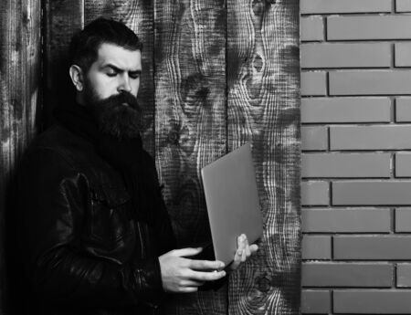 Bearded brutal caucasian hipster holding tablet and laptop