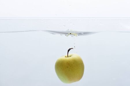 Apple washing in pure, transparent water, copy space. Green apple under water with trail of transparent bubbles.の写真素材