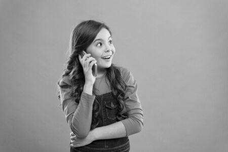 Glad to hear. Modern gadget. Upbringing and development. Little girl call mobile phone blue background. Cute kid hold smartphone. Mobile conversation. Mobile communication. Information and newsの写真素材