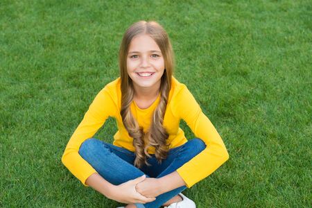 Hip and stylish. kid with curly hair. little beauty after visit to hairdresser. fashion and beauty. happy childrens day. spring holiday. carefree child on green grass. little girl with pleasant smileの写真素材