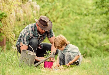 Little helper in garden. Make planet greener. Growing plants. Take care of plants. Day of earth. Boy and father in nature. Gardening tools. Planting flowers. Dad teaching little son care plants.の写真素材