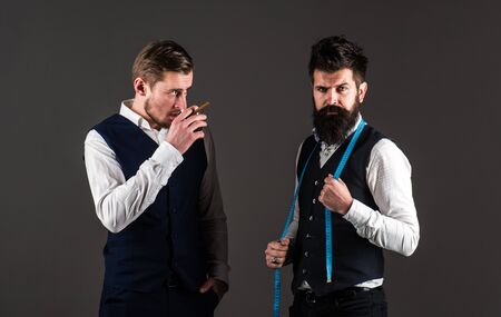 Tailor on strict face ready to take measurements, grey background.の写真素材