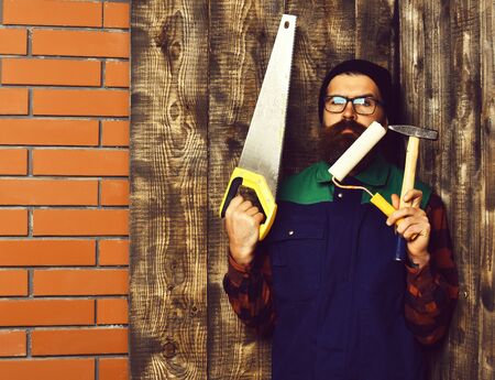 bearded painter holding various building tools with serious faceの写真素材