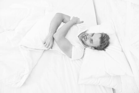 Sleep problems can lead to headaches in morning. Migraine headaches. Handsome man relaxing in bed. Snoring can increase risk headaches. Common symptom of sleep apnea. Causes of early morning headacheの写真素材